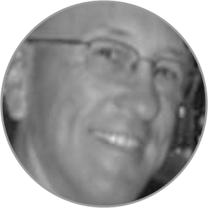 Smiling person in grayscale, wearing glasses.